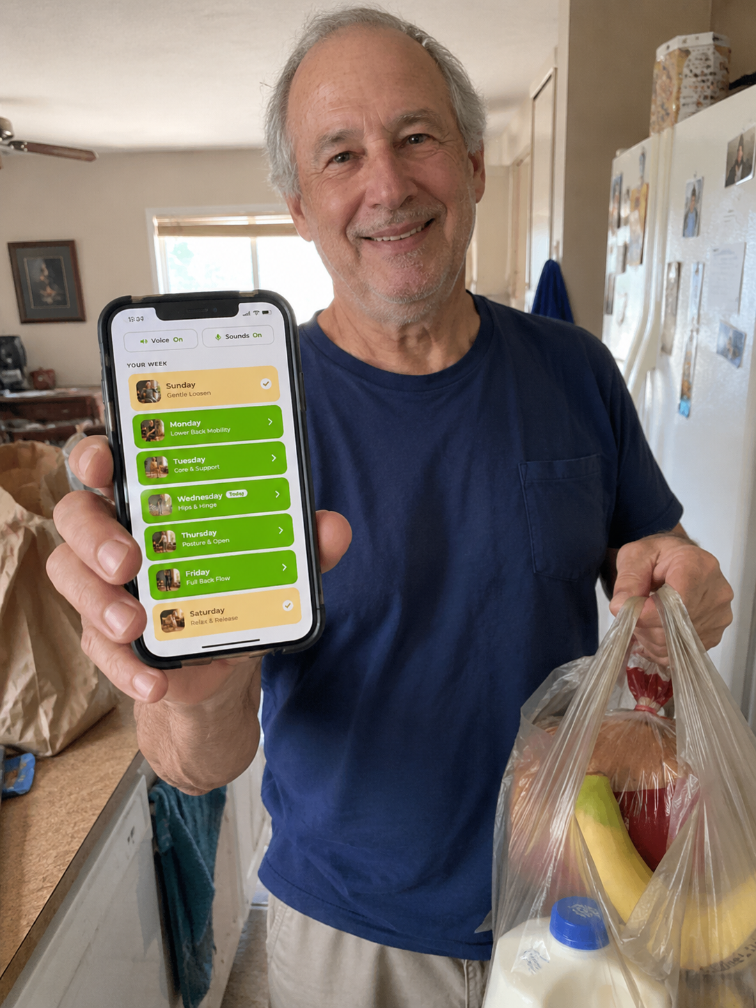 Robert, holding his phone with the program open, back home with the groceries.